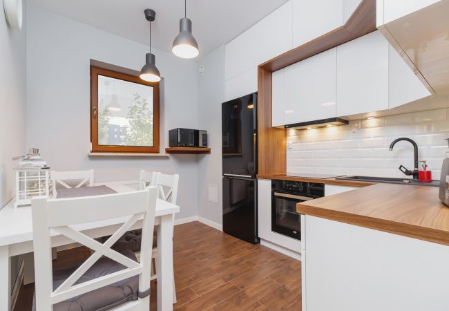 kitchen, kitchenette, stove, oven, fridge freezer, kettle, dishwasher, coffee maker, toaster, cupboards, dining area, dining table, chairs, apartment,